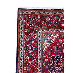 Persian indigo ground rug, the central crimson pole lozenge medallion surrounded by interlacing floral patterns, the main border with repeating plant motifs connected by scrolling branches