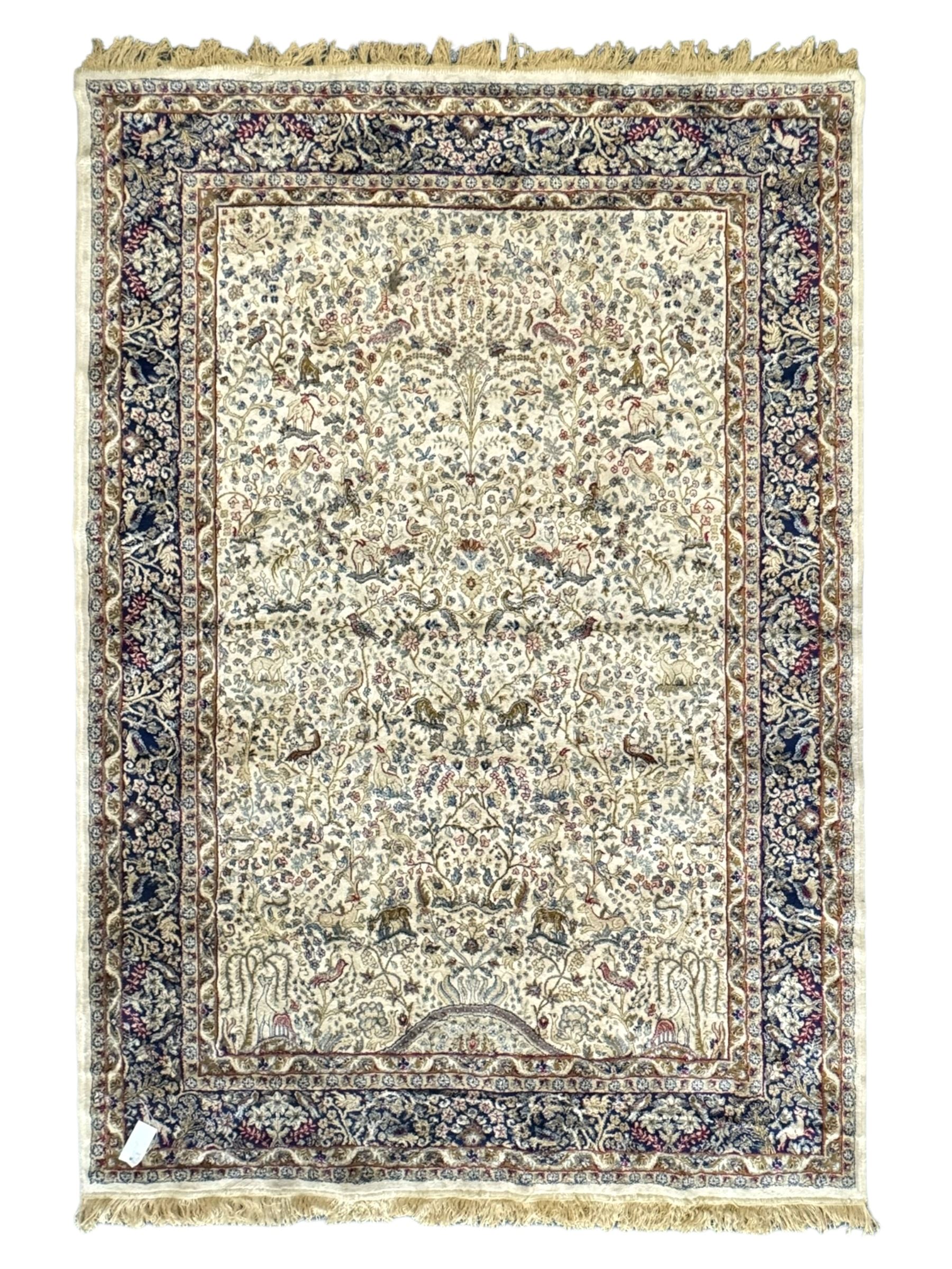 Persian Kerman ivory ground rug, the field adorned with naturalistic depictions of birds, animals and floral designs, framed by a multi-band border in blue and red tones