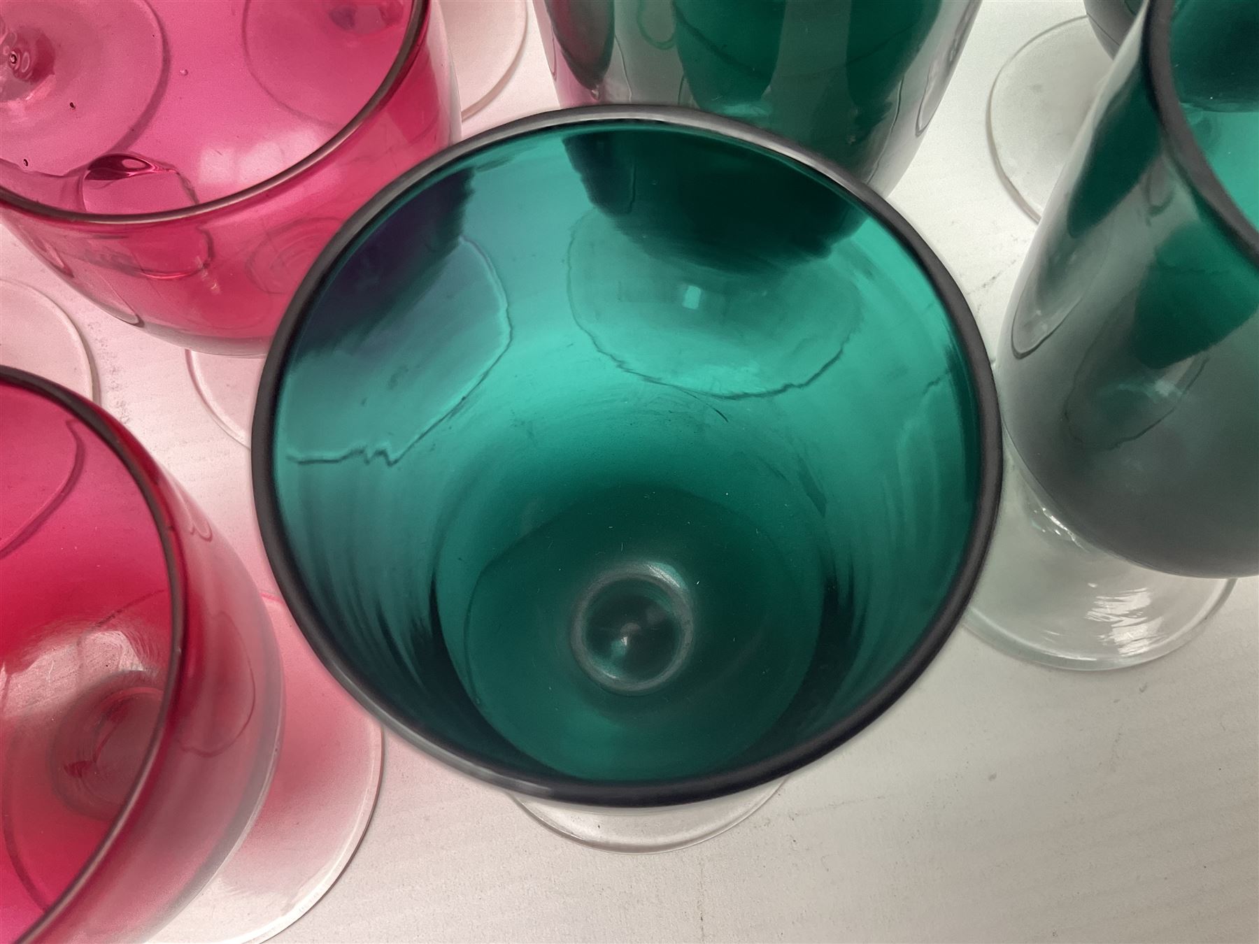 Collection of 19th century coloured glasses, to include nine cranberry glass punch cups, each with clear glass handle and foot and a set of six green glasses, with short clear stems, tallest H10cm