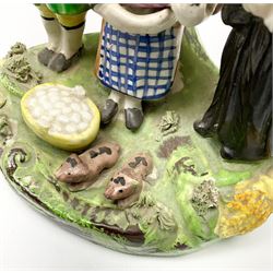 Two early 19th century Staffordshire figure 'Tithe Pig' groups, modelled as parson, farmer, wife and infant before bocage support, upon a moulded base detailed with piglets, wheat sheaves and baskets of eggs, each approximately H14.5cm