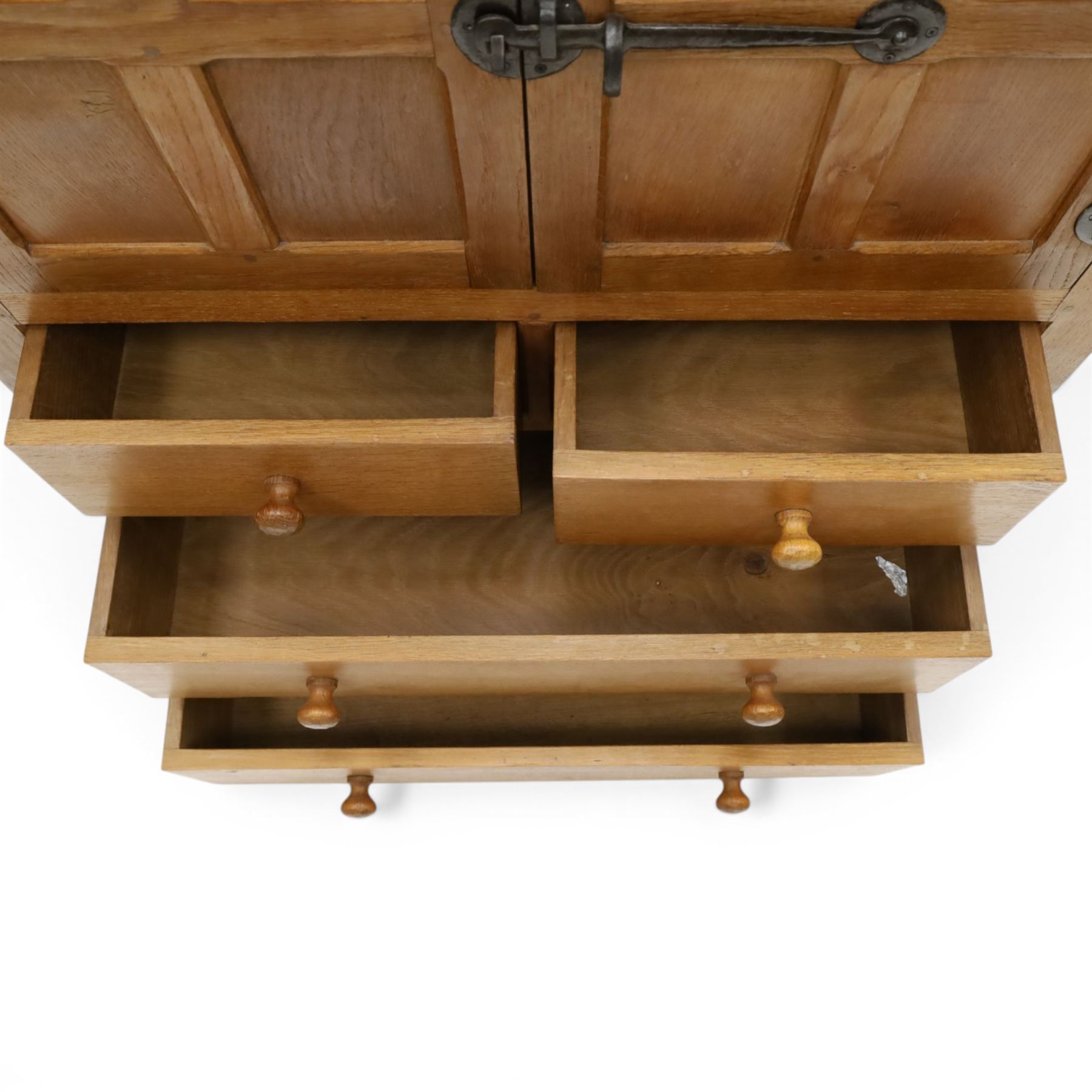 Mouseman - mid-20th century adzed and panelled oak tallboy chest, arcade carved cresting rail over two panelled cupboard doors with wrought iron fittings and latch, enclosing single shelf, over two short and two long drawers with lightly adzed facias and turned knob handles, raised on square supports, relief carved mouse signature, by the workshop of Robert Thompson of Kilburn