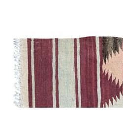 Kilim muted pink ground runner, decorated with rows of horizontal bands in muted tones, alternating with geometric triangular patterns along each band, fringed ends