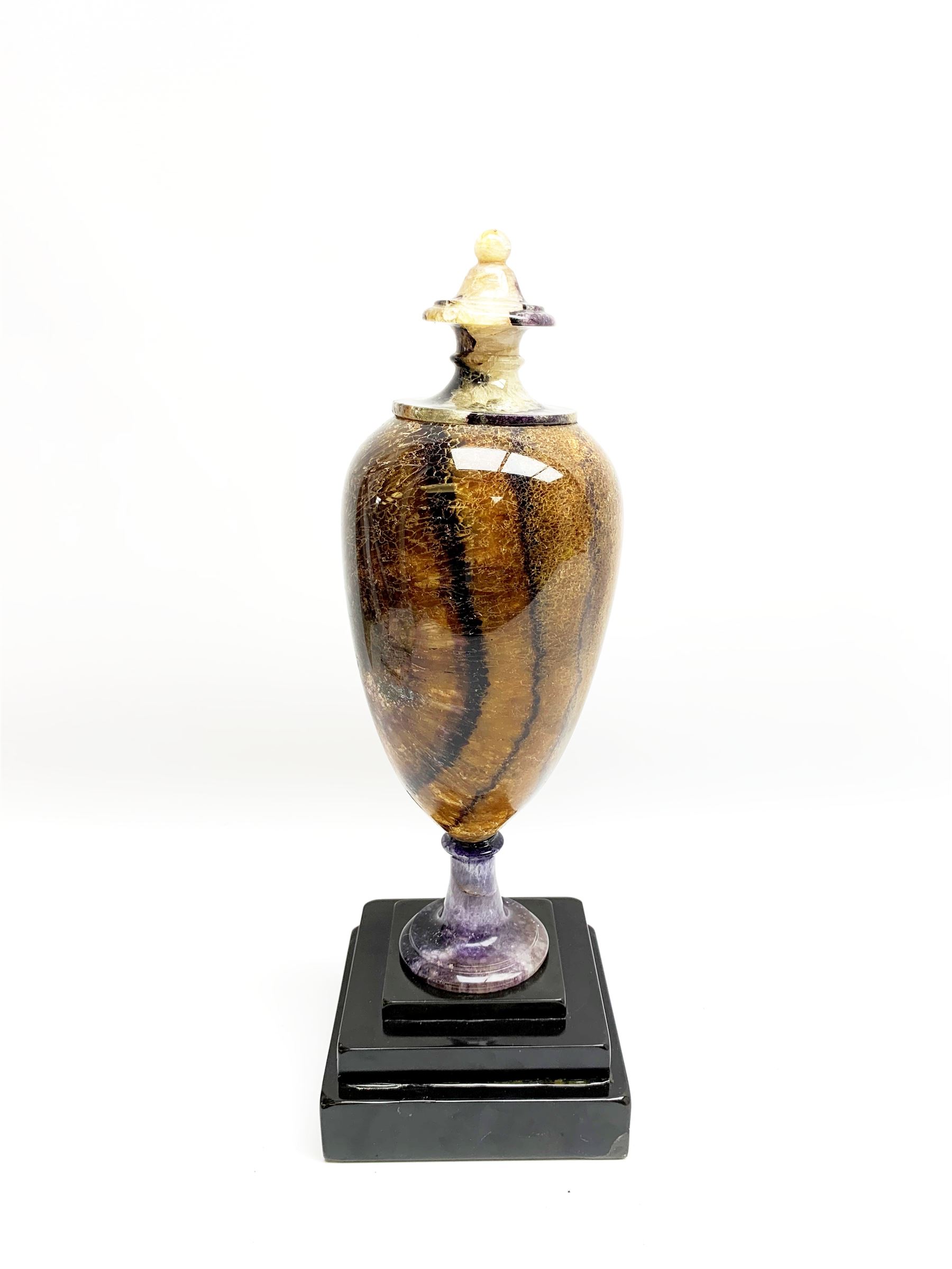 Early 19th century and later Blue John urn, Winnats one vein, of ovoid form with integrated cover and ball finial, upon a spreading circular base, and square stepped black lacquered base, H34.5cm