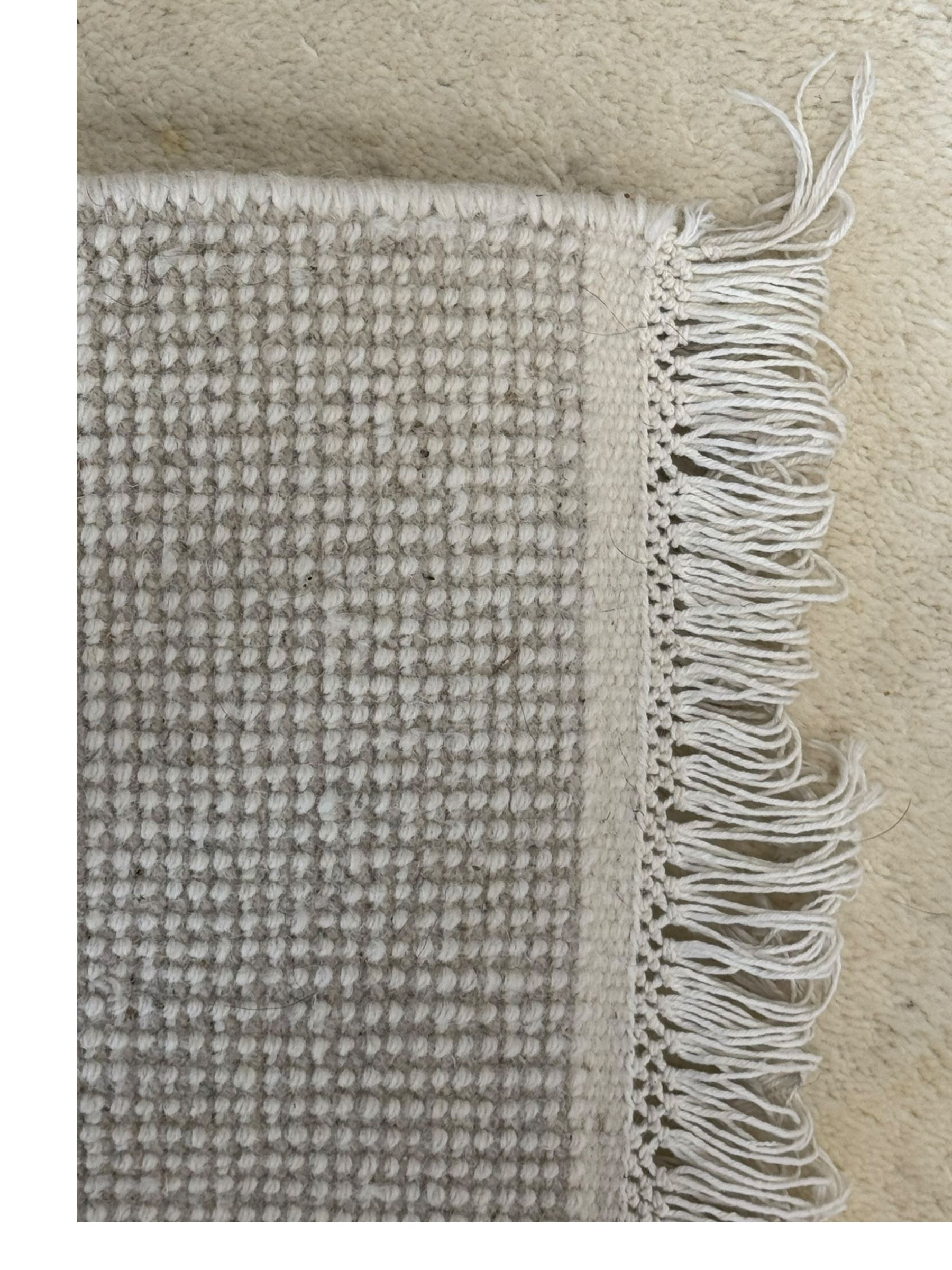 Contemporary Kayam hand-knotted Indian rug, plush wool pile in plain cream, ivory fringed edges on both sides 