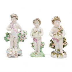 Derby porcelain model of a cherub holding a basket of flowers and wearing a chaplet, H13cm, another Derby cherub holding a basket of flowers and another Derby style cherub, together with a 19th century Staffordshire Ralph Wood type pearlware figure emblematic of Autumn, holding grapes and a goblet (4)