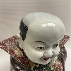 Japanese Fukusuke good fortune figure, modelled as a kneeling male figure holding a fan, dressed in traditional Samurai robes, H15.5cm