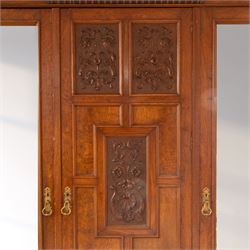 Late Victorian oak and burr oak three-section mirror wardrobe, central door with three carved panels with shell and acanthus decoration, fitted with four drawers and four tray drawers, linen sides with bevelled mirrored panel doors with hanging space, plinth base, and dental cornice