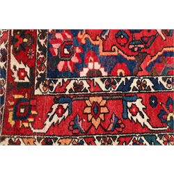 Vintage Persian Heriz crimson ground rug, the field decorated with a central stylised urn and bird of paradise motifs, the guard  lines with repeating stylised plant motifs of geometric form