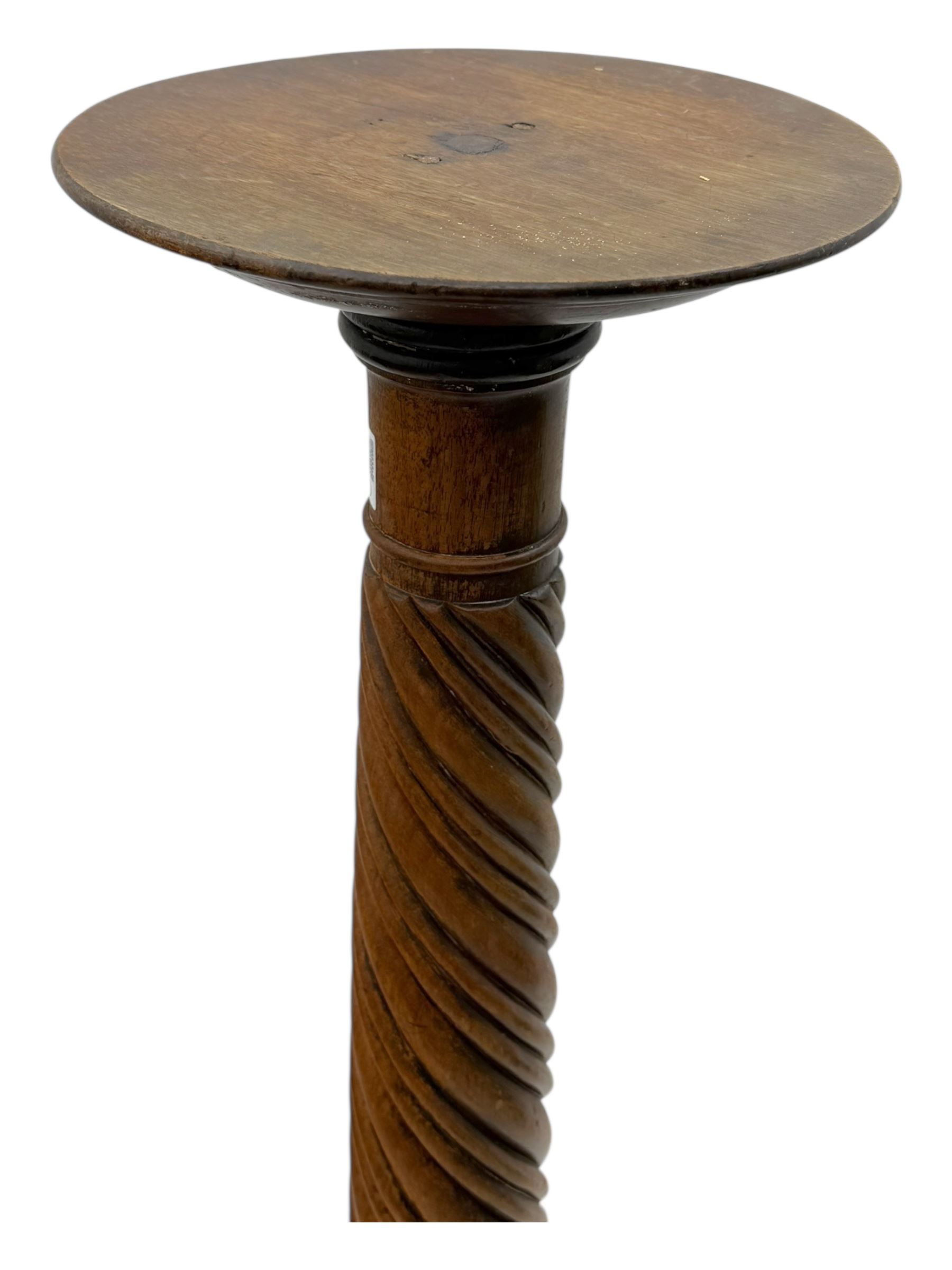 Late 19th century mahogany torchère stand, with circular top above a twisted and foliate carved collumn, on a scroll carved tripod base, on cabriole legs