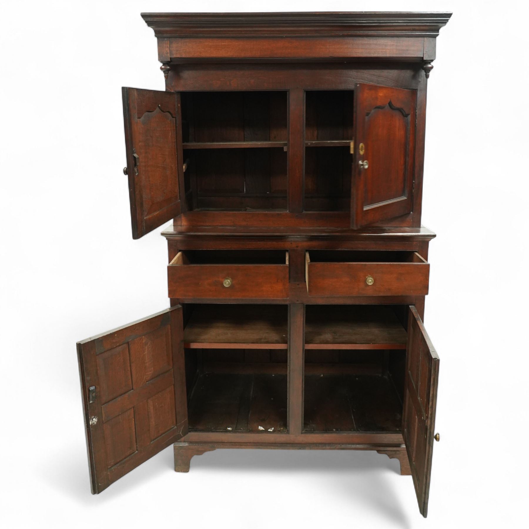 Early 19th century Welsh oak kitchen cupboard, the projecting cornice with twin cupboard doors, the rectangular base over two frieze drawers and panelled cupboard doors, raised on bracket feet, with fielded and arched panel variants to front and sides