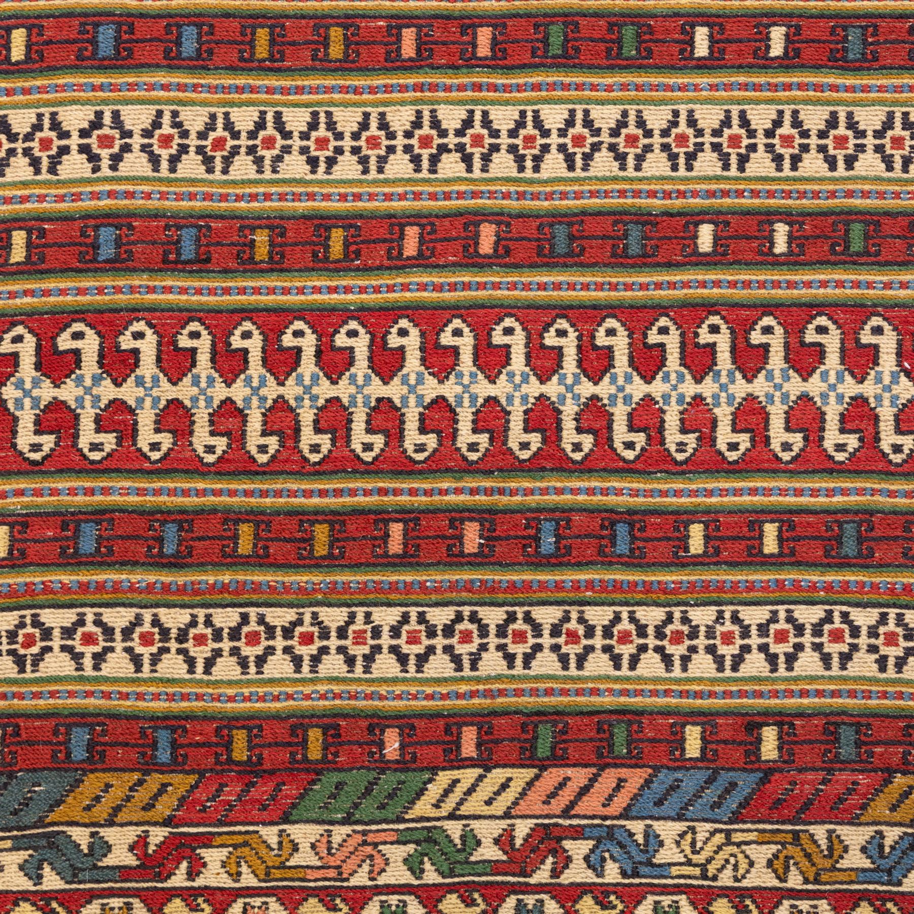 North East Persian Sumak flatweave kilim runner, elongated field decorated with horizontal bands of stylized geometric motifs in madder red, ivory, indigo green, and ochre enclosed by bold geometric borders  