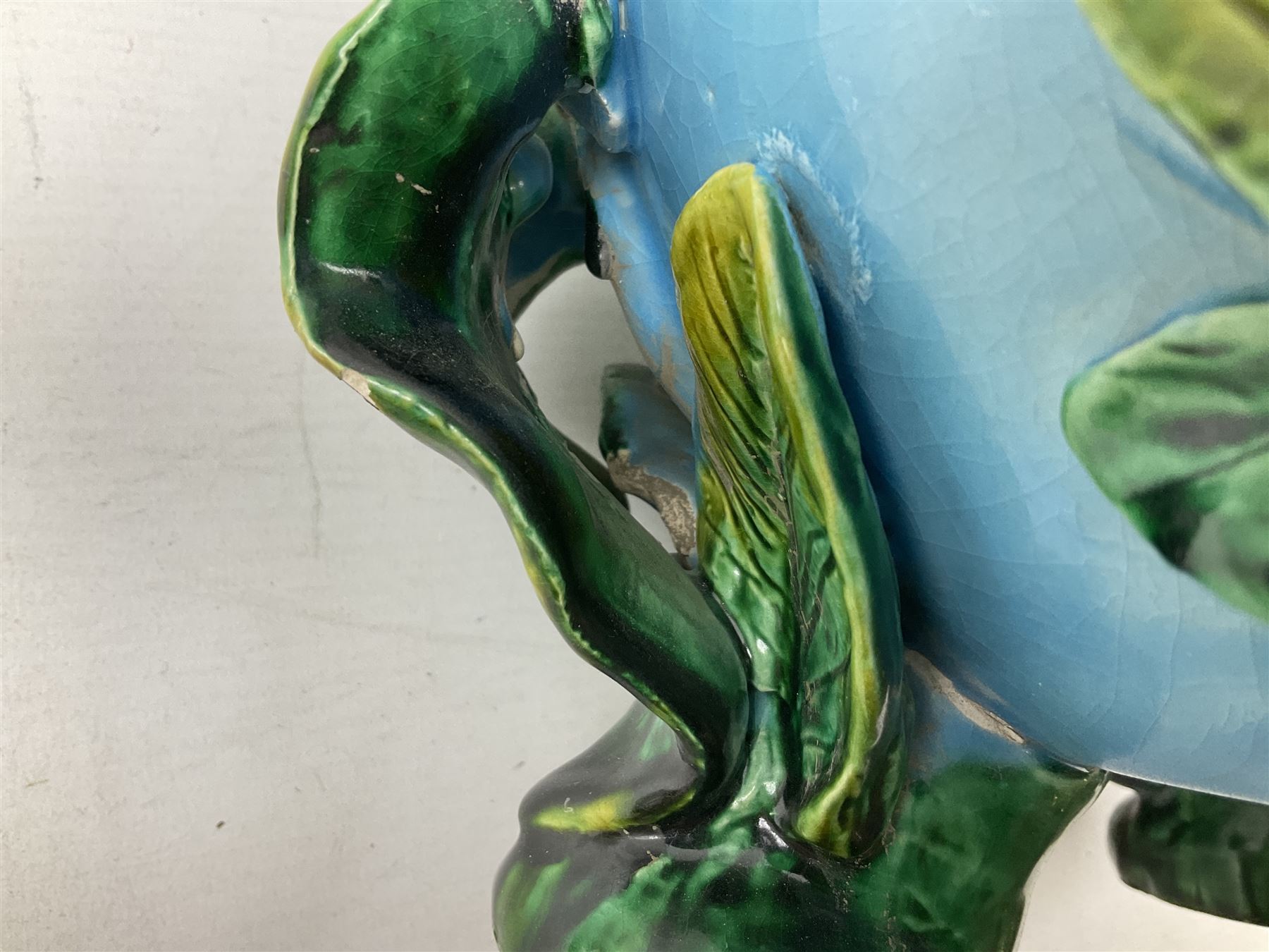 George Jones style majolica jardiniere of globular form, supported on four feet formed from modelled lily leaves growing up the side of the pot, with swallows flying amongst the white lily flowers, all set against a blue ground, with a pink interior, H27cm