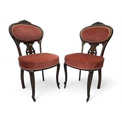 Pair of Edwardian inlaid rosewood salon chairs, upholstered in dusky pink fabric with gimp trim, oval backrest with carved crest rail with central shell motif and pierced splat, on cabriole supports terminating in castors