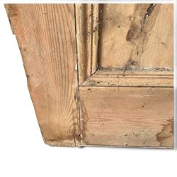 Victorian stripped pine four-panel door, the raised fielded panels within carved foliate and moulded surrounds, with iron lock and fittings and brass knob handle