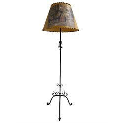 20th century wrought metal standard lamp, decorated with scrolls and on tripod base, with conical shade depicting hunting scene (H172cm); and a wrought metal wall hanging flower pot holder (W92cm)