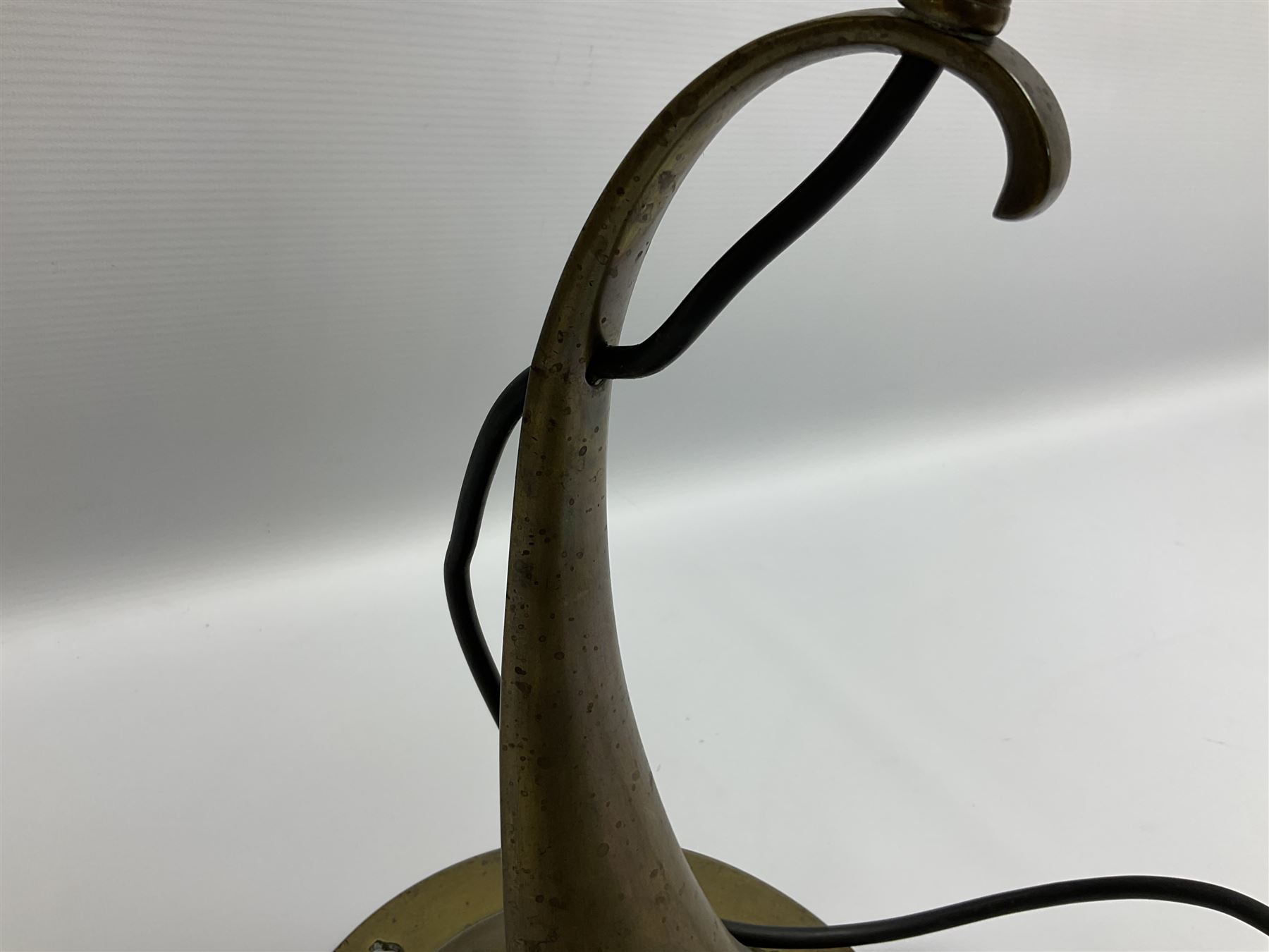 Arts & Crafts Jesson, Birkett & Co, brass table lamp or wall light, designed by Thomas Birkett, the tapering stem with adjustable ball pivot supporting a conical shade with tapering final with ball terminal, upon a circular domed base pierced for wall mounting, shade positioned upright overall H57cm

Often misattributed to Arthur Stansfield Dixon for Birmingham Guild of Handicraft, this particular lamp was designed by Thomas Birkett.
In the late 1890's Birkett worked as a metalwork at the Birmingham Guild, before later joining the Faulkner Bronze Company which went on to become Jesson, Birkett & Co in 1904. The lamp features in lighting catalogues from the firm under the model no E490.

