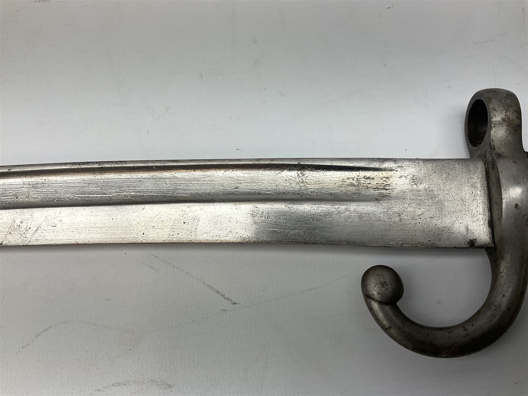 Turkish Model 1874 sword bayonet with 57.5cm curving steel fullered blade and chequered black grip, in steel mounted leather scabbard L75.5cm overall