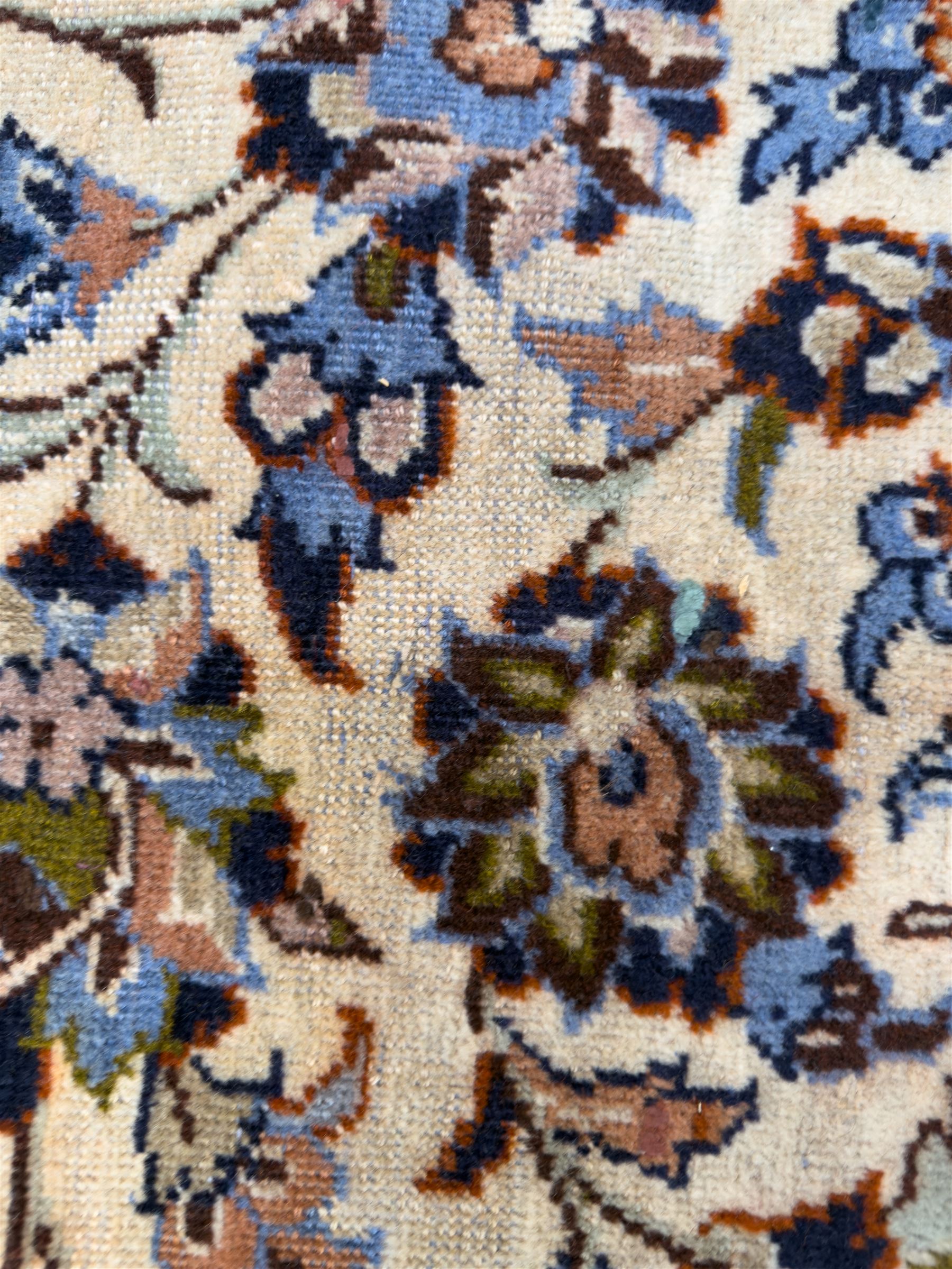Central Persian Najafabad hand-knotted carpet, the ivory field with a central floral medallion radiating palmettes and arabesques in tones of blue, lilac and tan, enclosed by a wide navy border of scrolling vine and rosette motifs, with red spandrels and multiple guard stripes