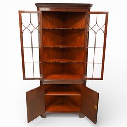 William Tillman - Early 20th century mahogany corner cabinet, the projecting moulded cornice with dentil detail over a glazed upper section enclosed by a pair of astragal glazed doors with Gothic arched tracery, the interior fitted with shaped shelves, above a moulded waist and a lower cupboard enclosed by two panelled doors with shaped fielded panels, raised on bracket feet