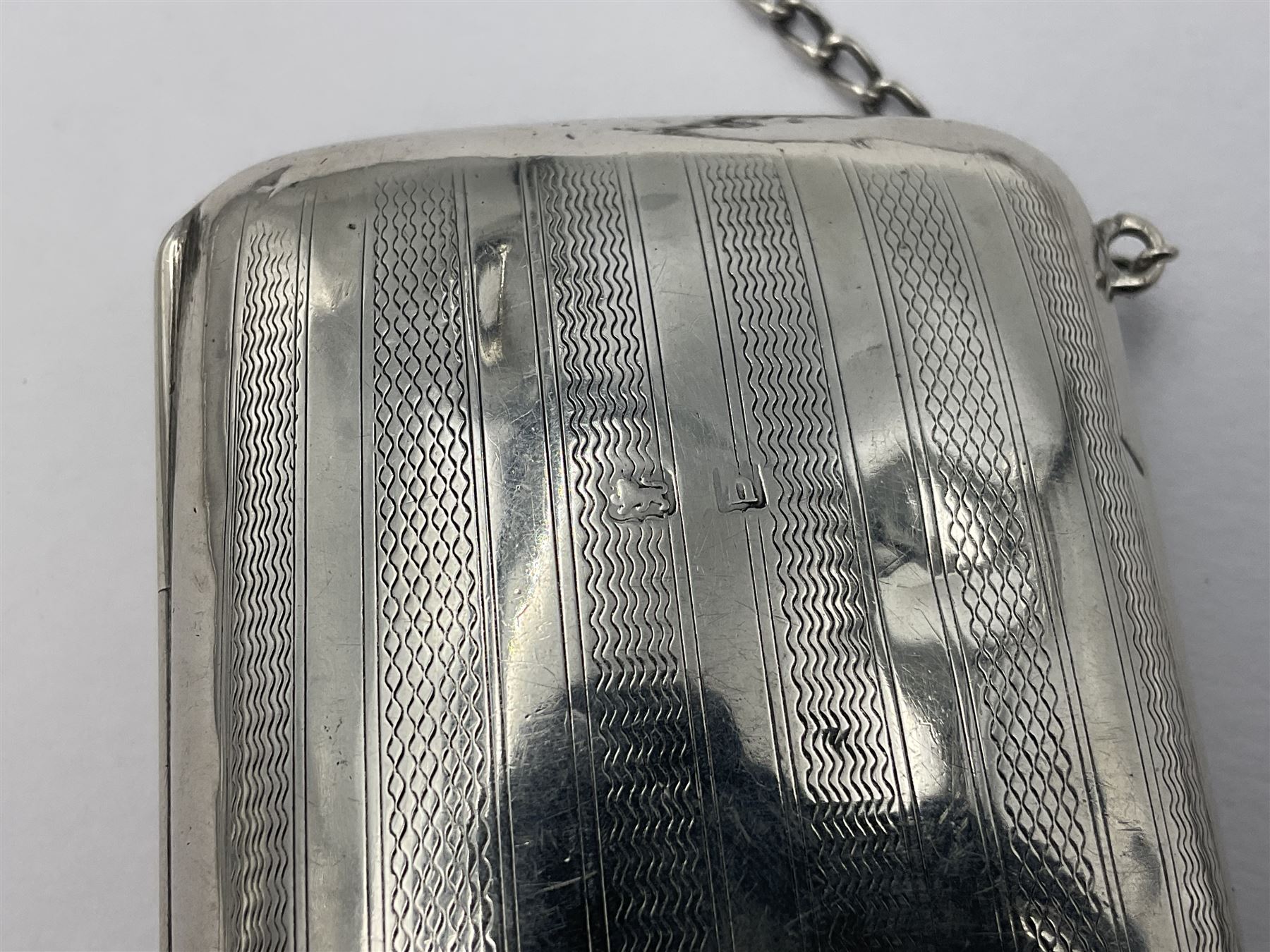 Early 20th century silver mounted coin purse, with leather interior and finger chain, hallmarked Samuel M Levi, Birmingham 1917, together with a similar Edwardian example, with engraved initials and engine turned decoration, hallmarked Birmingham 1907, maker's mark worn and indistinct, largest W11.3cm