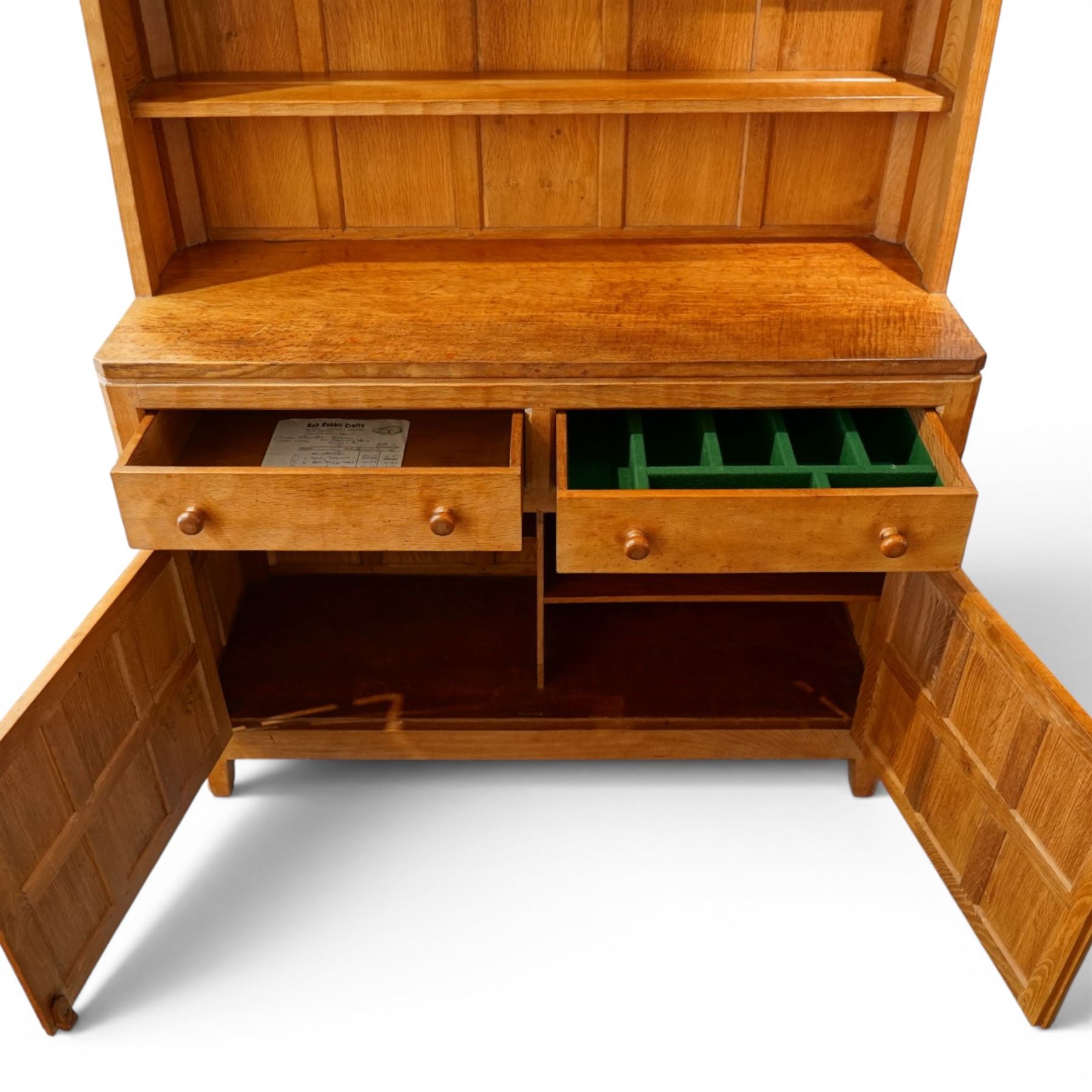 Rabbitman - adzed oak Welsh dresser, scalloped cornice above two plate racks, adzed and panelled sides, the lower integrated section with adzed oak top, over two drawers above twin cupboard doors with blackened metal latch and hinges, carved rabbit to the right hand side, by Peter Heap of Wetwang