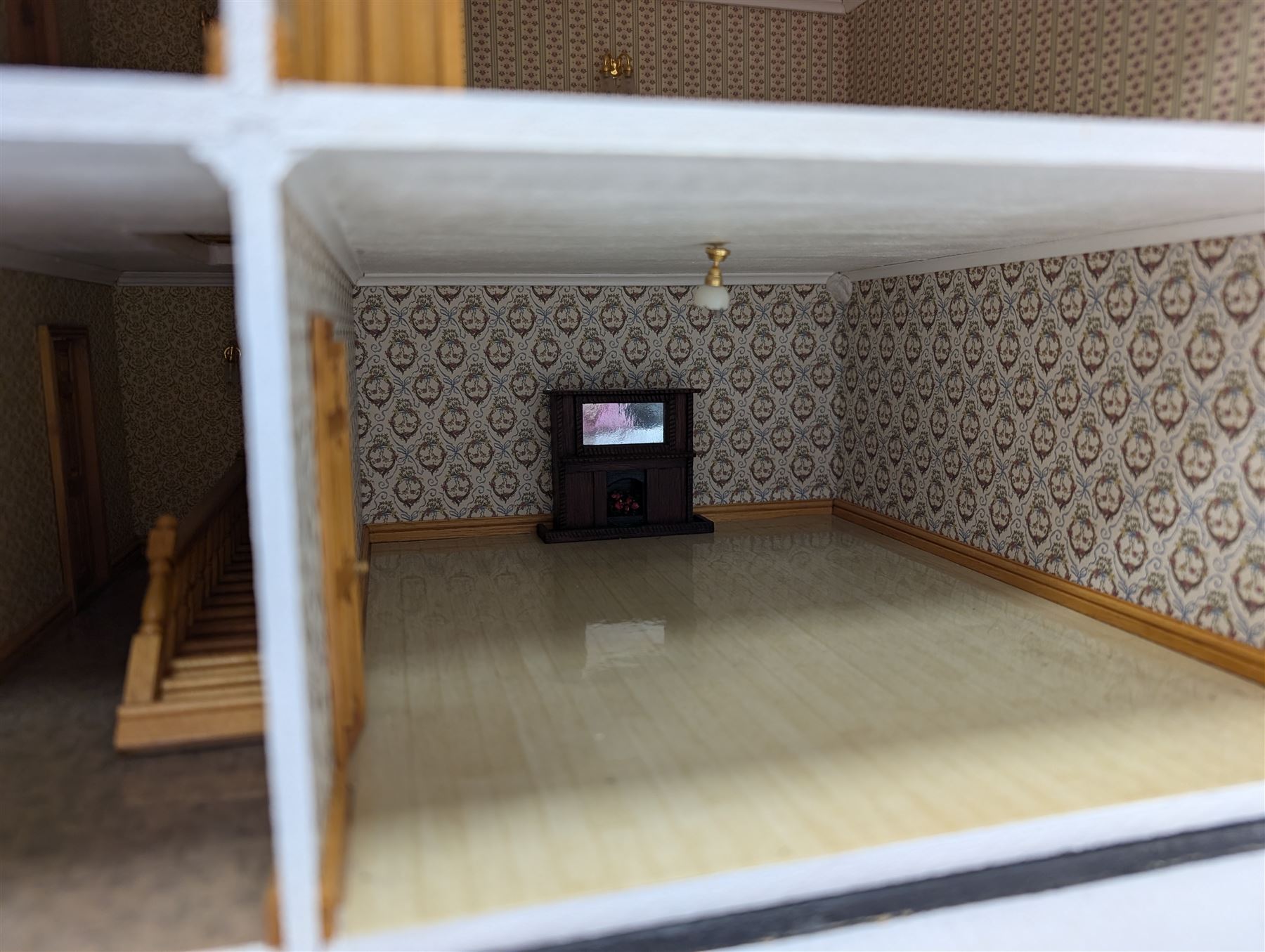 1:24 scale four-storey tudor-style dolls house, with black and white exterior, balcony garden, glazed panelled windows and wooden shingle roof, with decorated interior and wired fireplaces and lighting, H65cm, W58cm, D31cm, 