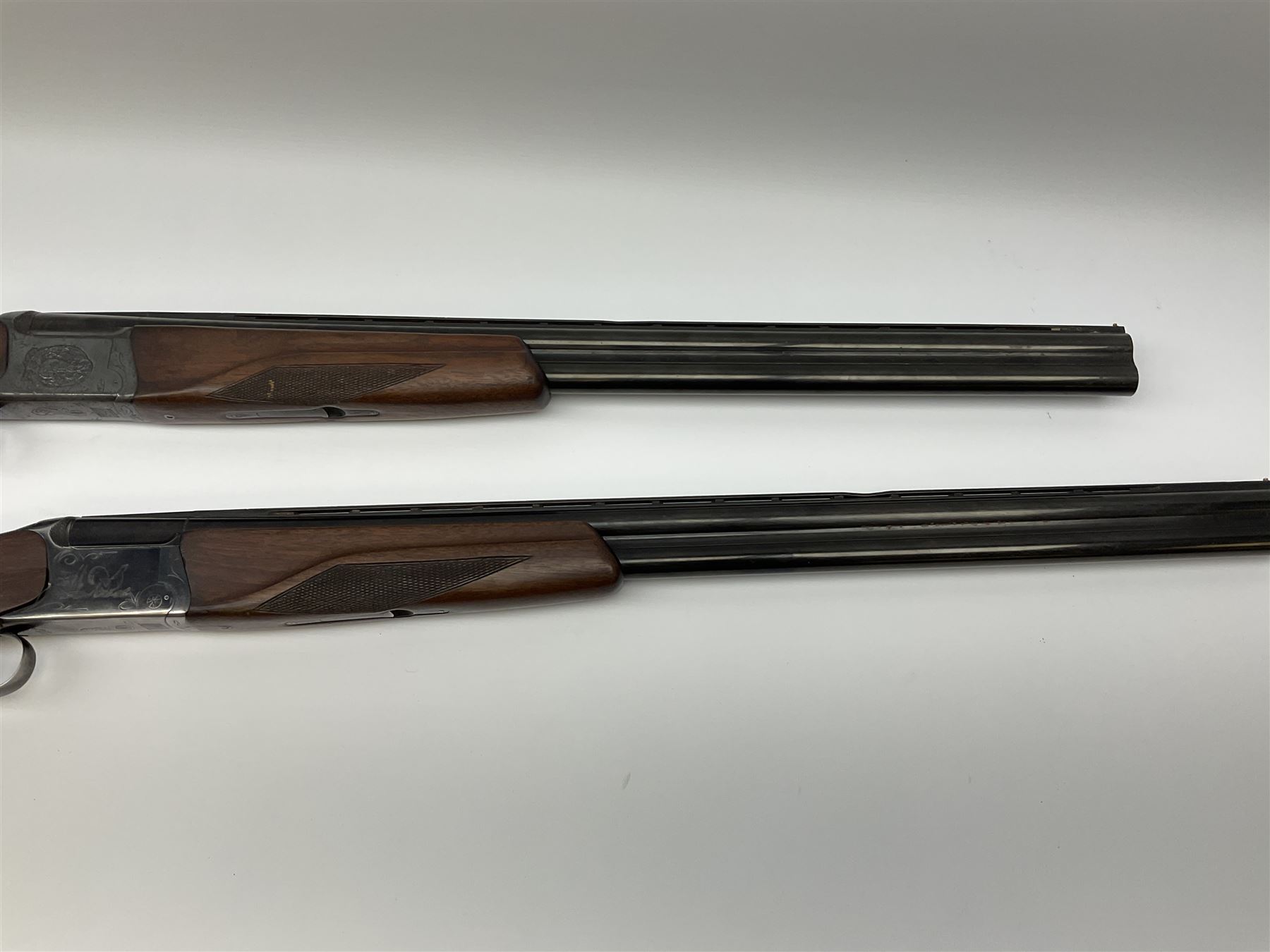 Two Russian Baikal 12-bore over-and-under double barrel boxlock non-ejector sporting guns; one with 68.5cm barrels, walnut stock with chequered pistol grip and fore-end and thumb safety, serial no.520545, L111cm overall; the other with 72.5cm barrels, walnut stock with chequered pistol grip and fore-end and thumb safety, serial no.012448, L114.5cm overall (2) SHOTGUN CERTIFICATE REQUIRED