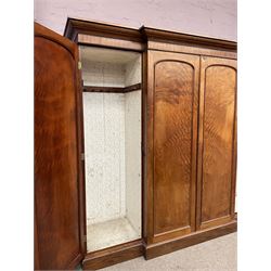 19th century figured mahogany quadruple breakfront press wardrobe, projecting cornice with banded frieze over arch panelled doors, the interior fitted with three sliding trays over two short and three long graduating drawers with recessed brass handles, flanked by two hanging cupboards with hooks