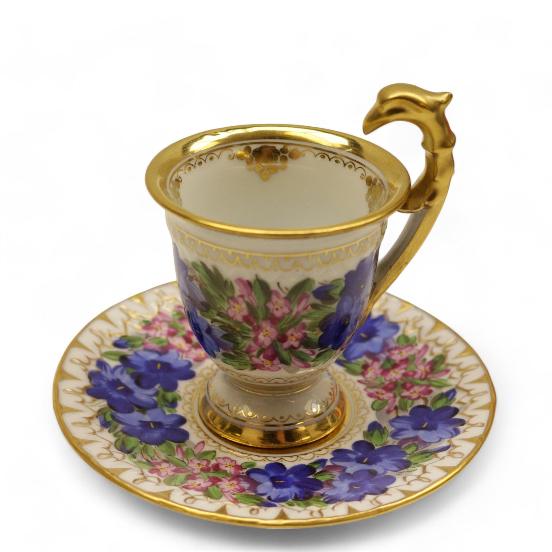 Four early 19th century Dresden cups and saucers, comprising twin handled chocolate cup and cover, decorated with floral swags, cup and saucer decorated with children dancing and two others 