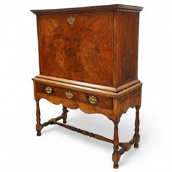 Early 18th-century George I walnut bureau cabinet on later stand, moulded rectangular cornice above fall front, inlaid oval burr walnut panel opening to reveal a fitted interior of drawers, pigeon holes, and a central cupboard door, with baize-lined writing surface above a long drawer over a shaped apron and turned legs joined by a turned stretcher, lacks key, later brass strut supports