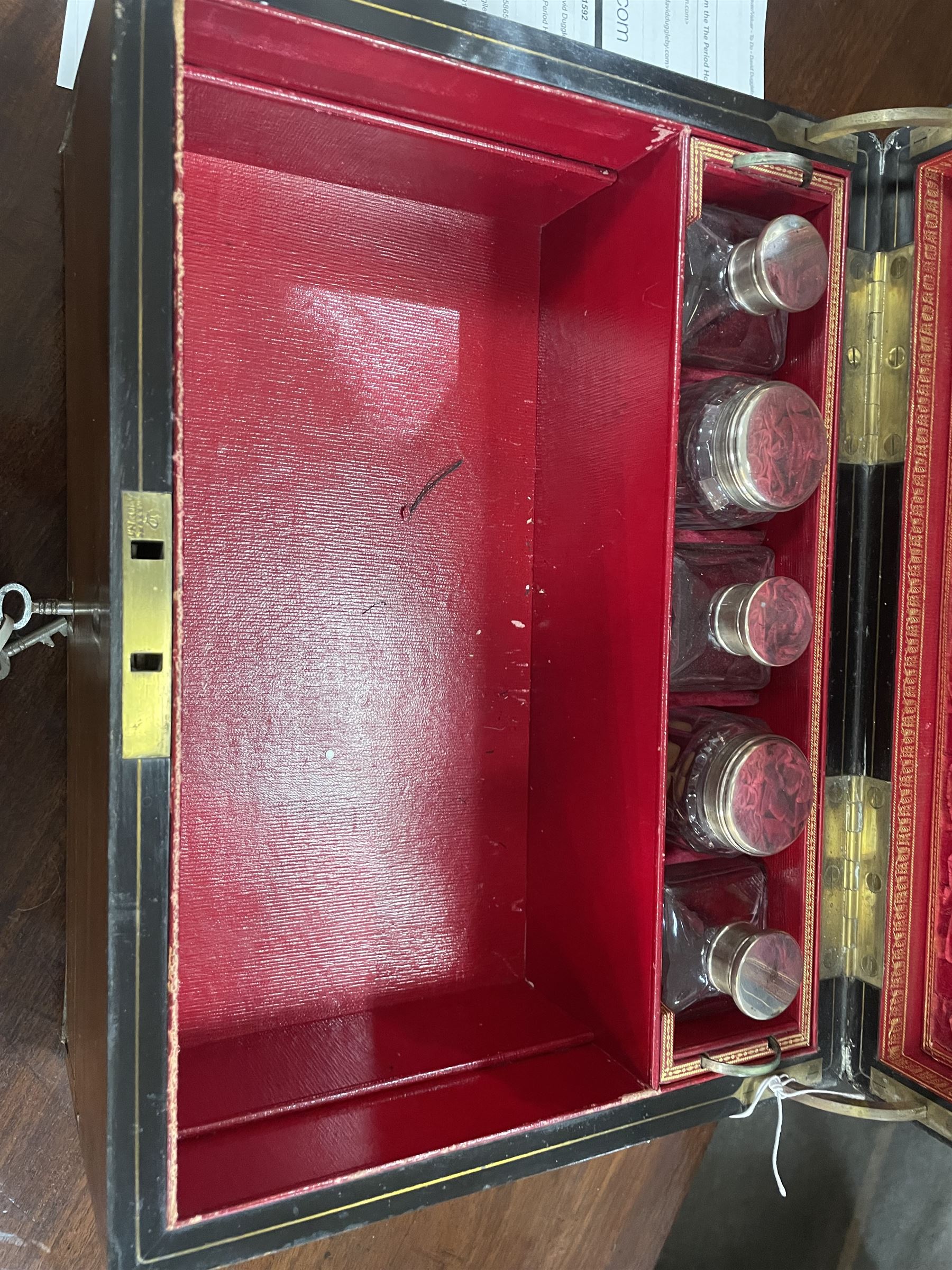  Victorian brass inlaid rosewood dressing table box, retailed by F.L. Hausburg, Liverpool, the lid centred by a brass cartouche, opening to reveal letter store to lid underside, above a fitted interior, with ten mounted cut glass jars, bottles and manicure set, within lift out leather trays, above jewellery drawer, with key, H17cm D24cm