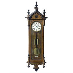 German - 19th century 8-day weight driven Vienna wall clock in a walnut and ebonised case, with an ogee arched pediment and ebonised finials, canted corners and fully glazed door, curved base with a carved arcade and pendants, two part porcelain dial with with a spun brass bezel, Roman numerals, pierced gothic hands and subsidiary seconds dial, rack striking movement with a dead-beat escapement and maintaining power, striking the hours and half hours on a coiled gong, visible ebony pendulum with a brass bob and two brass cased weights.