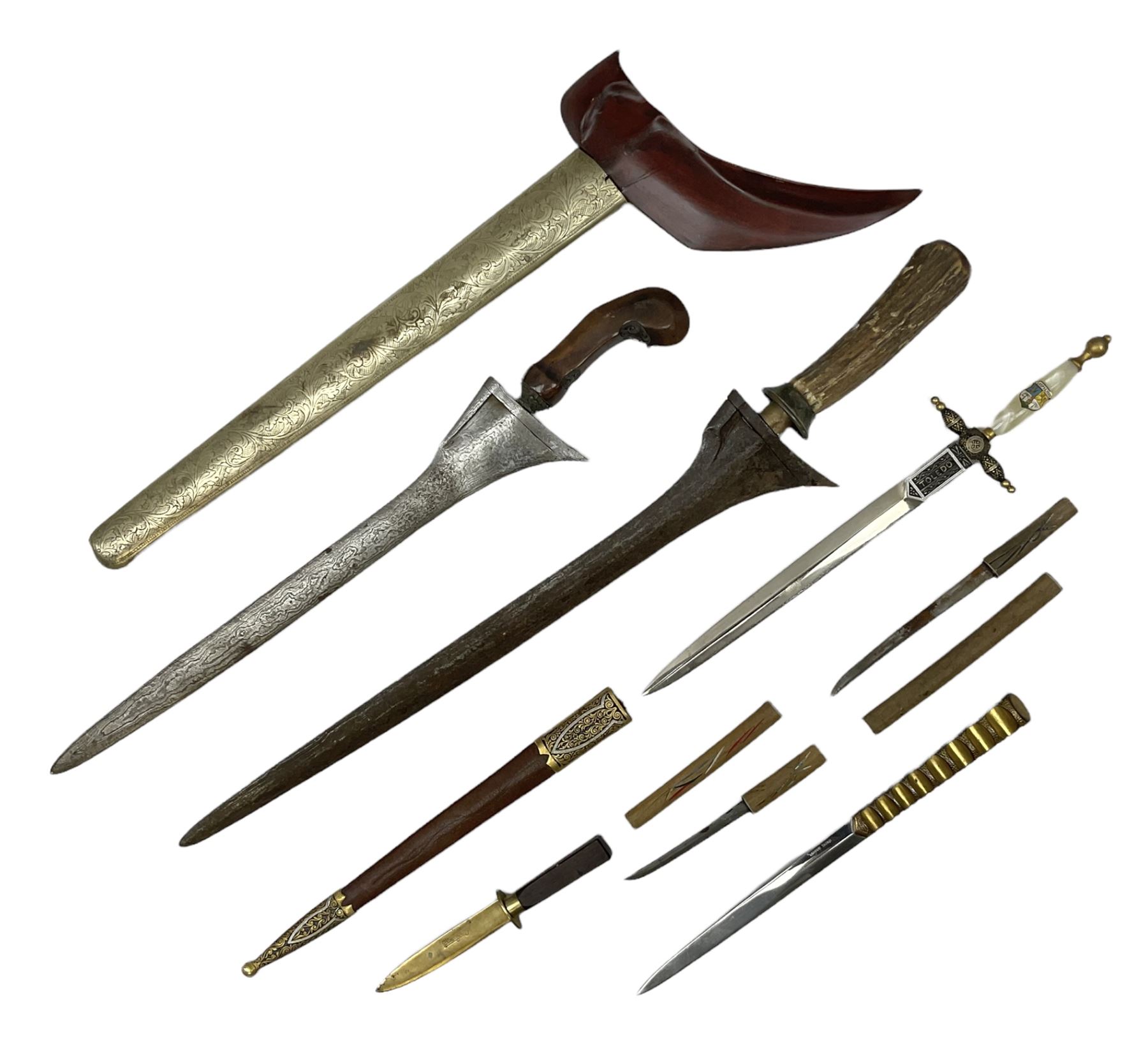 Malayan Kris dagger, the 31.5cm double edged straight heavy damascus blade with copper ferrule; carved hardwood grip; in large wooden throated scabbard with floral decorated white metal covering L47.5cm overall; a kris blade with adapted antler grip; and five various small daggers/letter openers (7)
