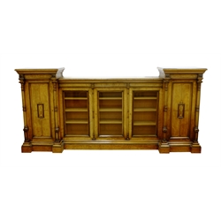  Large late Victorian oak and walnut drop centre inverted break front library bookcase, projecting cornice above gilt geometric frieze, three central glazed doors enclosed by panelled doors with central tablet carved with flower filled urns, full turned and fluted architectural columns, probably by Marsh, Jones and Cribb, W307cm, H142cm, D57cm, - Provenance Cayley family, Brompton Hall, Brompton near Scarborough auction sale 1950s  