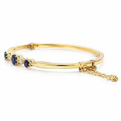 Early 20th century 18ct gold sapphire and diamond hinged bangle, the front set with three round cut sapphires and spaced by two old cut diamonds, total sapphire weight approx 1.15 carat