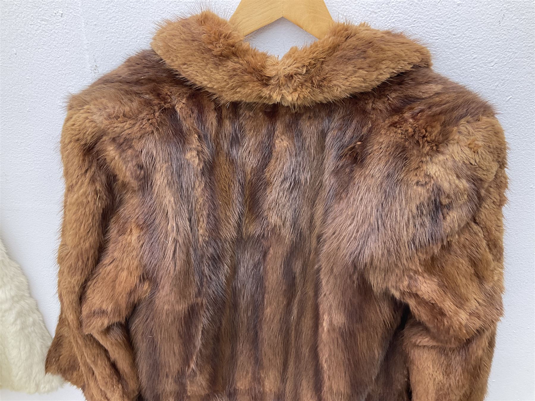 Brown mid length musquash fur coat by National Fur Company together with white rabbit cape