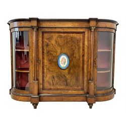 Victorian figured walnut credenza, shaped and moulded top over central panelled door with Sèvres design porcelain floral plaque, enclosed by two turned and satinwood inlaid columns with gilt metal Composite capitals, applied gilt metal bands, two flanking curve glazed doors, lower moulded plinth base, on turned feet