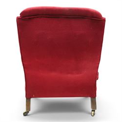 Victorian walnut framed reading open armchair of reclined position, the high sprung back and deep seat upholstered in crimson fabric with matching loose seat cushion, turned arm terminals over turned feet terminating to brass castors