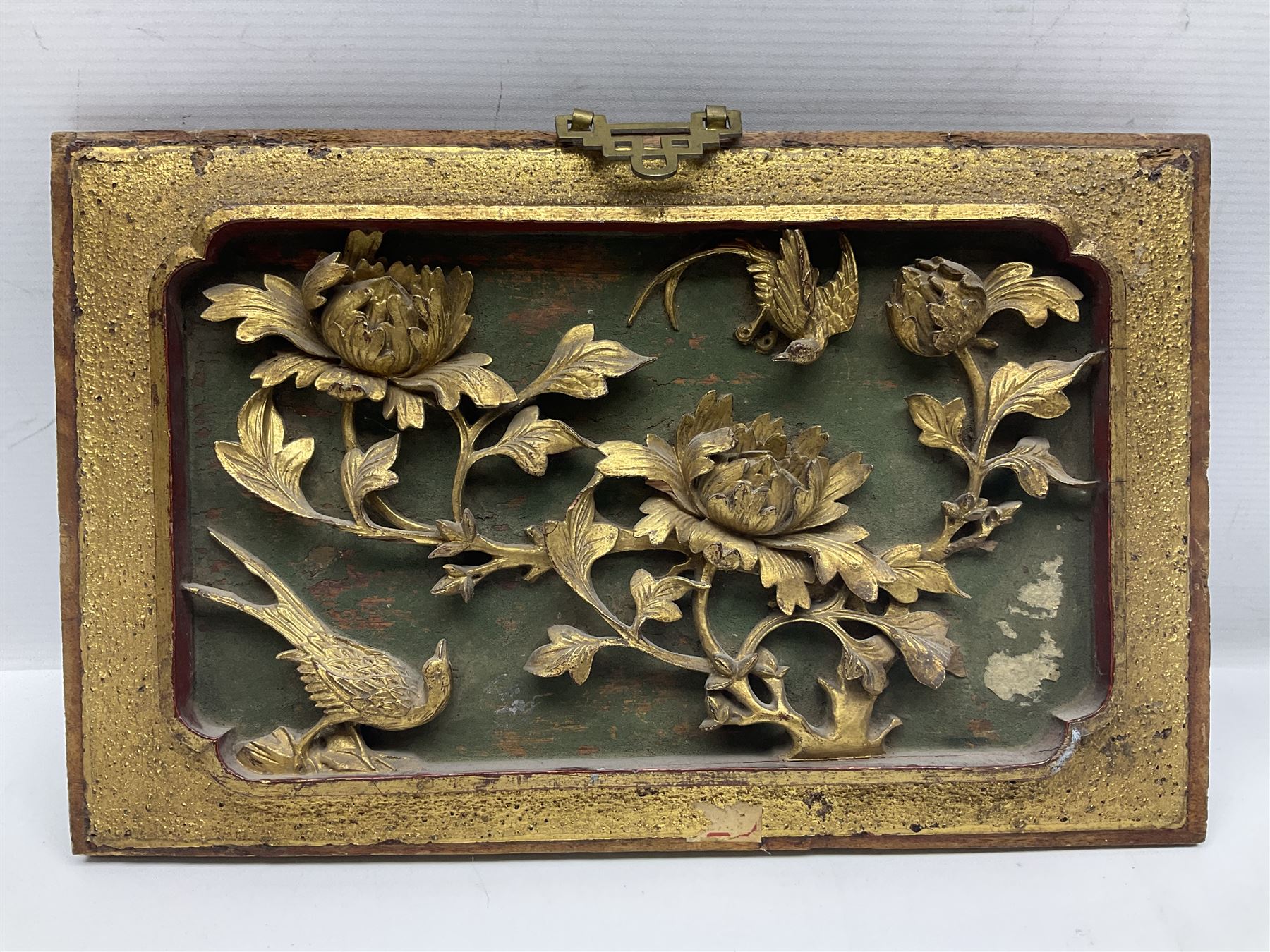 Two carved oriental wall hangings, the first example gilded depicting a temple and garden scene, the second figures in a garden, L49cm