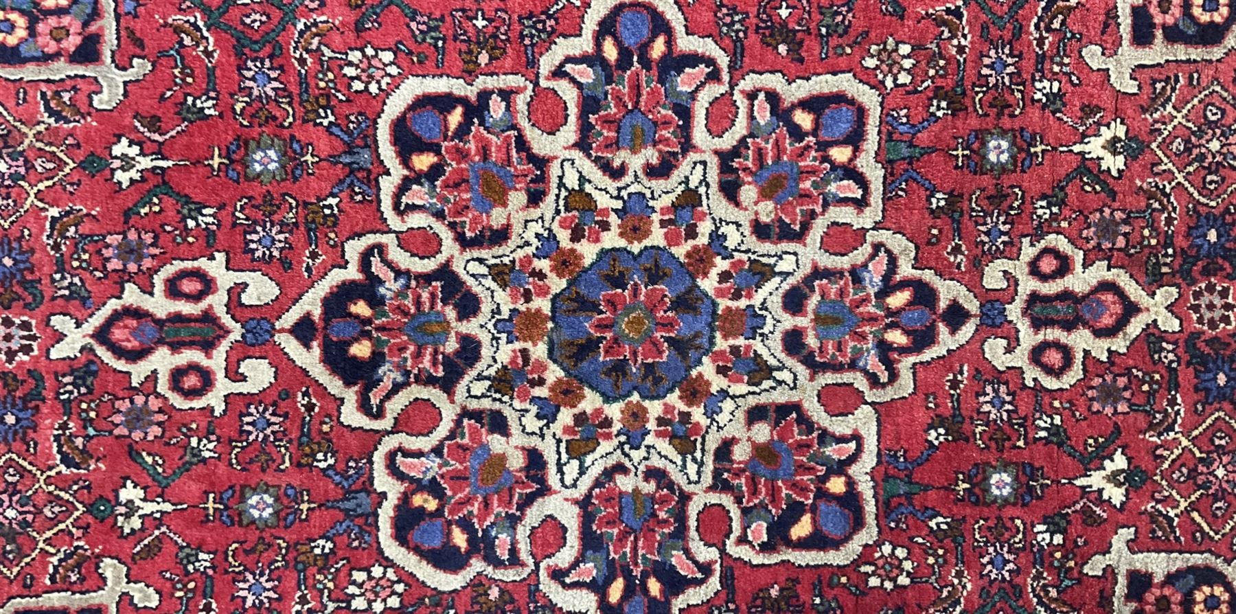 Persian Hamadan crimson ground rug, central floral pole medallion with matching spandrels, the guarded indigo border with interlaced palmettes