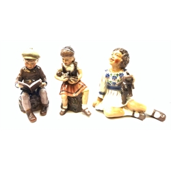  Three Royal Copehagen figurines designed by Dahl Jensen, the first modelled as a girl with elephant toy, the second as a girl with doll, (a/f), and third as a seated boy reading a book, each with printed mark beneath, first H14.5cm.  