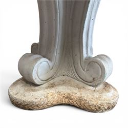 Weathered cast stone garden table, circular top etched with central floral medallion, the edge with repeating chevron motifs, raised on a quadriform S-scroll pedestal with stepped and chevron carved base