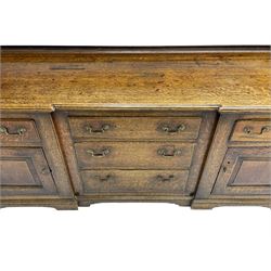 George III oak dresser, projecting dentil cornice over three heights plate rack enclosed by fluted uprights, the dresser fitted with five drawers and two panelled cupboards, canted corners with fluted quarter columns, on bracket feet
