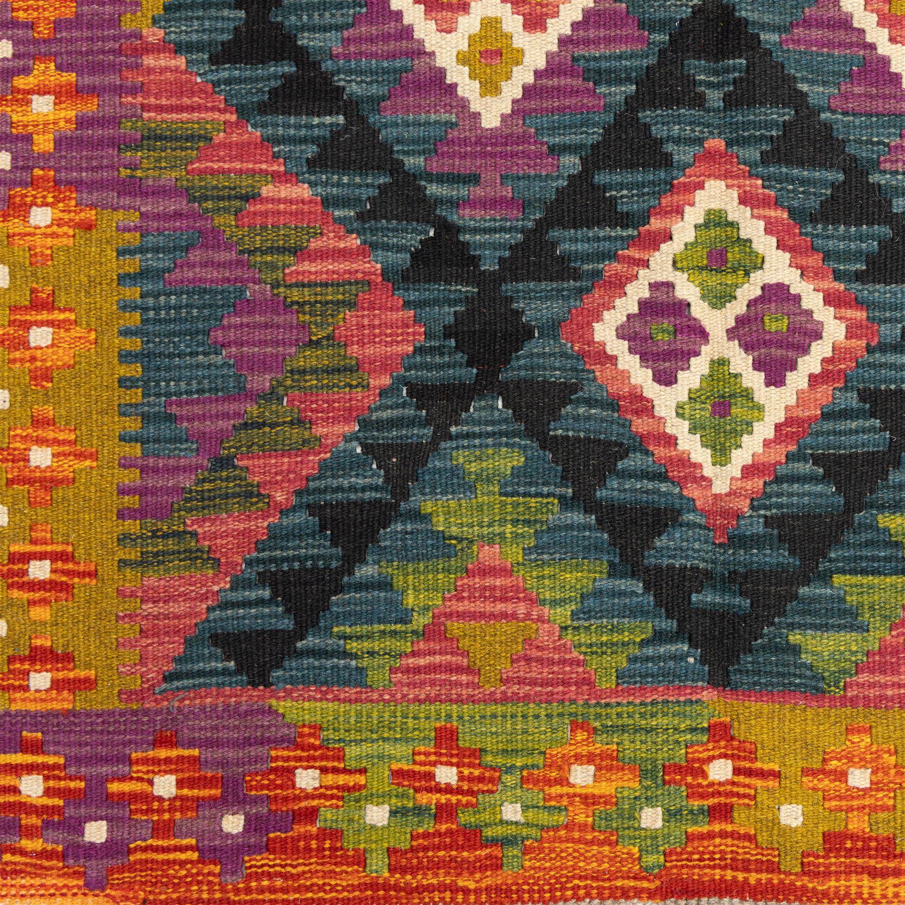 Chobi flatweave kilim runner with a repeating nested diamond medallion design in live green, rust, teal, purple, and ivory, framed by  a multicoloured geometric border