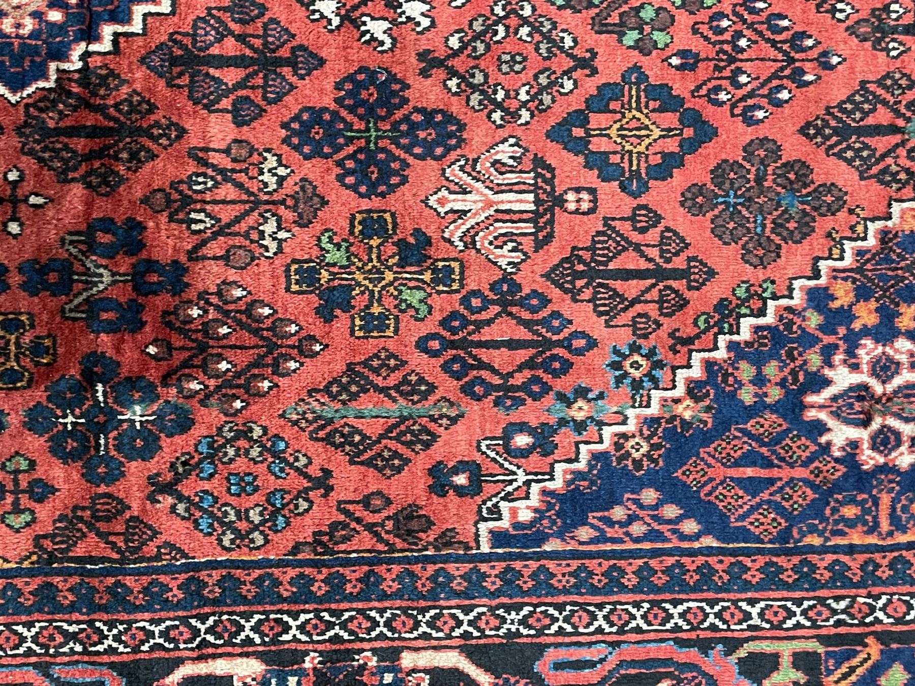 Persian Joshgan red ground rug, the medallion, field and spandrels decorated with clusters of Pitrak and tree of life motifs, the border with repeating design decorated with stylised plant motifs, within guard stripes