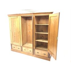 Late Victorian large pitch pine triple wardrobe, projecting cornice, central mirrored door flanked by two others above three drawers, plinth base