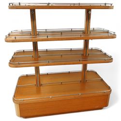 Mid-20th century retail display stand, of stepped rectangular tiered form with four graduated adjustable shelves, each with rounded corners and fitted with tubular chrome safety rails, supported by central chrome-mounted wooden uprights over a plinth base