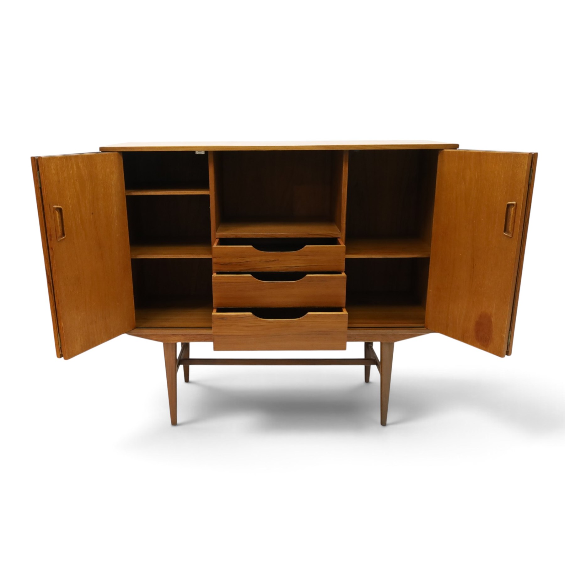 Alfred Cox - mid-20th century teak cabinet, rectangular top over two bifold doors with inset handles, opening to reveal three central graduating drawers surrounded by assorted shelves, raised on tapering supports united by H-stretcher, stamped to inside of drawer