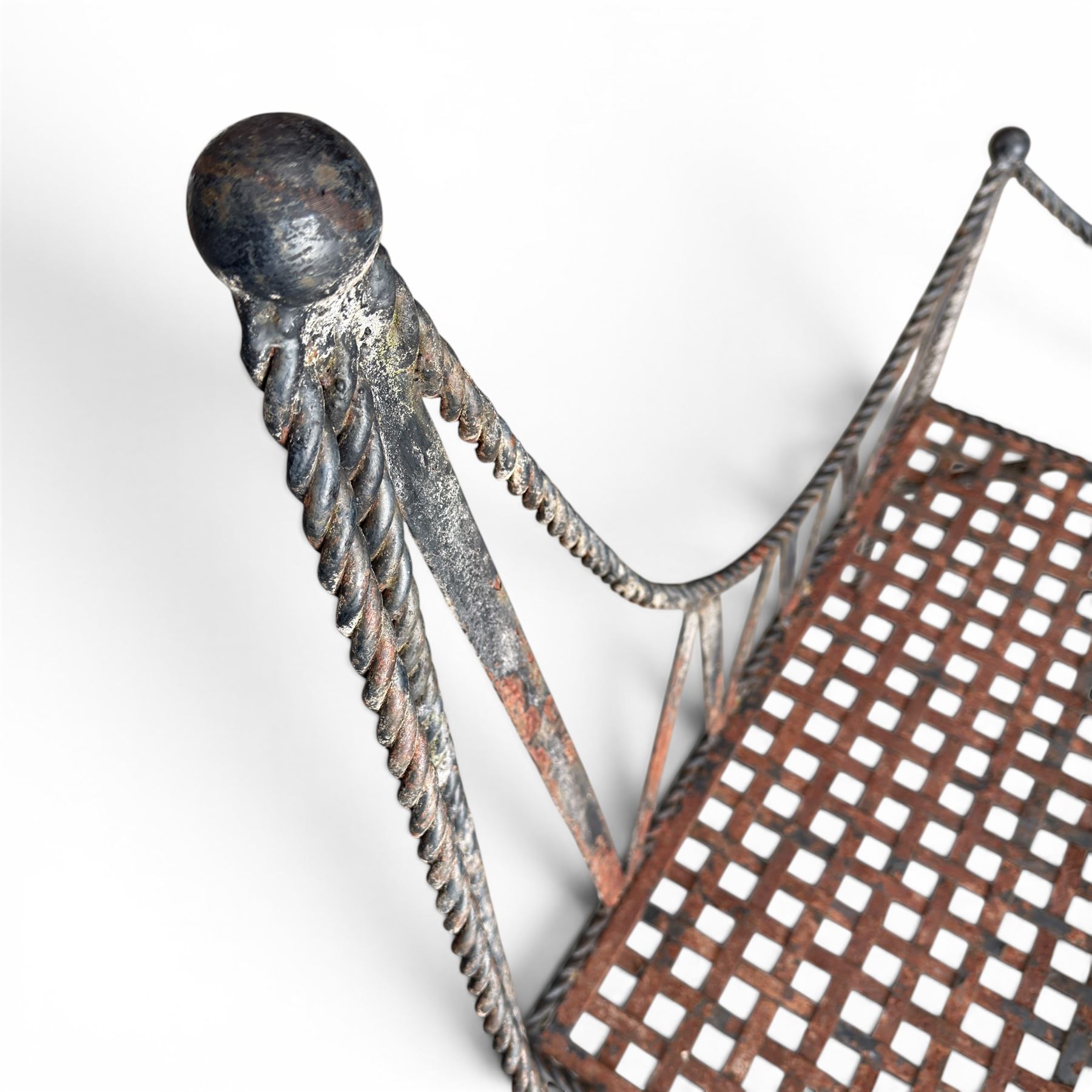 Victorian design wrought iron garden bench, with asymmetrical rope-twist frame, arched back and sides over out-swept arm terminals with ball finials, flanking a lattice seat, in antique black-painted weathered finish