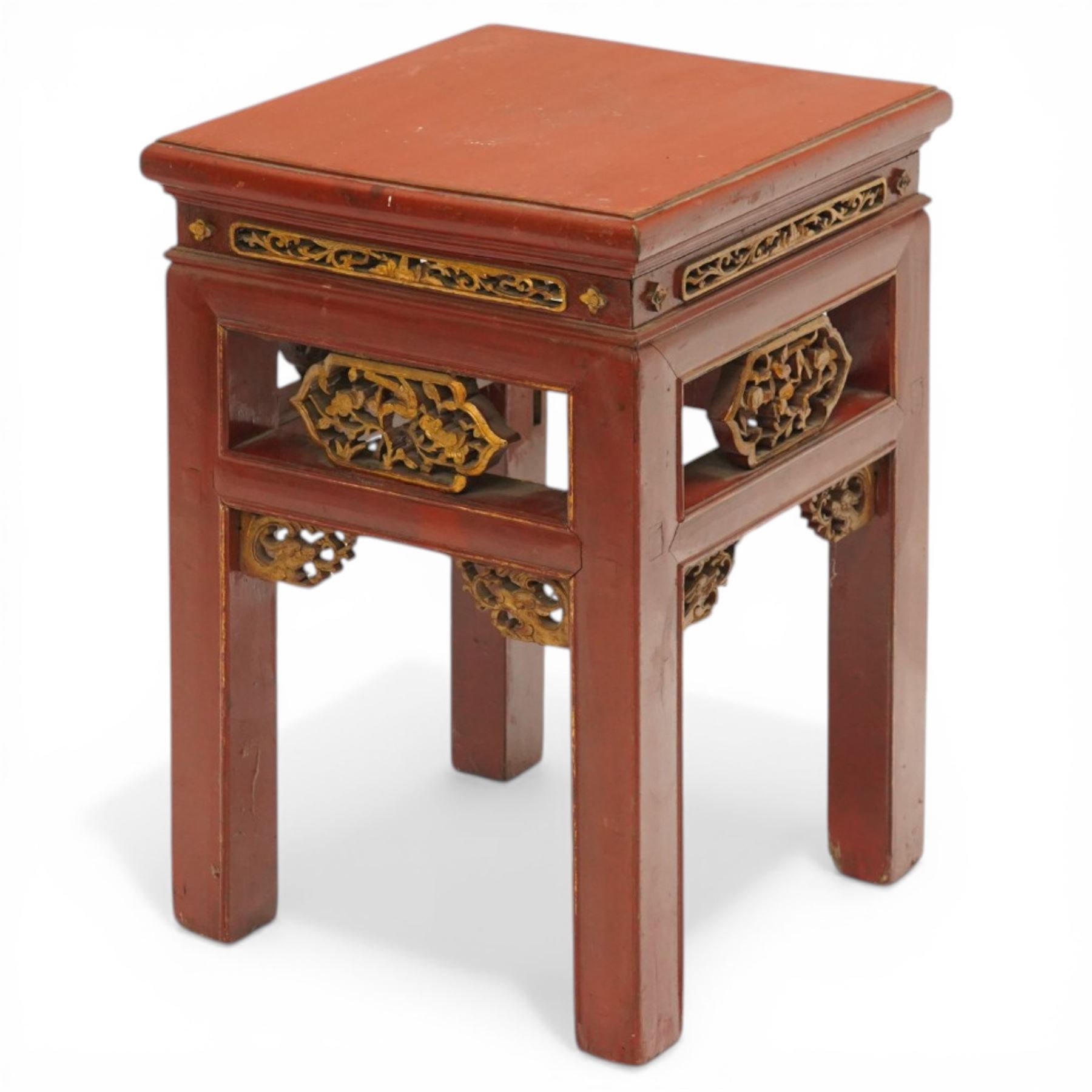 Early 20th century Chinese red lacquered occasional table, rectangular top over a pierced frieze decorated with carved giltwood floral panels and brackets, raised on moulded square tapering supports